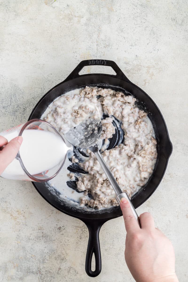 adding the milk to the sausage to make the gravy.