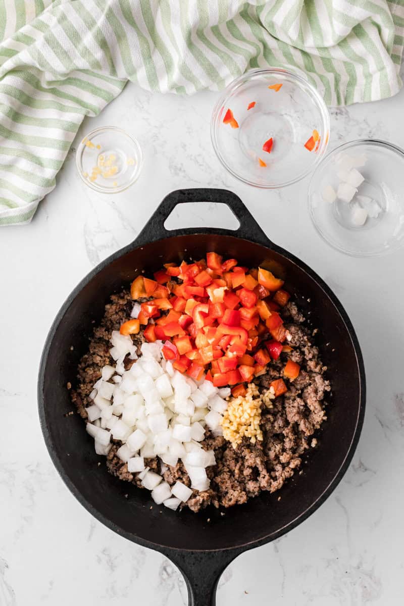 cooking the sausage, peppers, onions and garlic in a skillet.