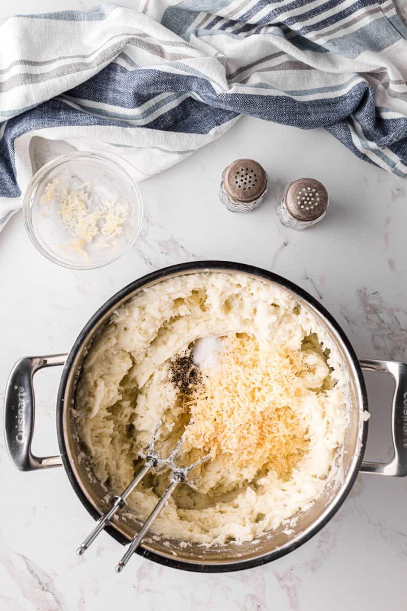 adding the salt and pepper and parmesan cheese to the mashed potatoes.