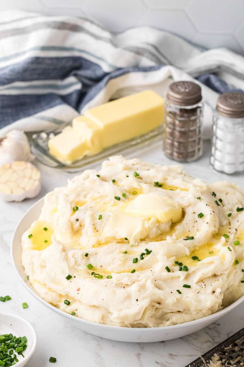 garlic mashed potatoes topped with butter in large white bowl for serving.