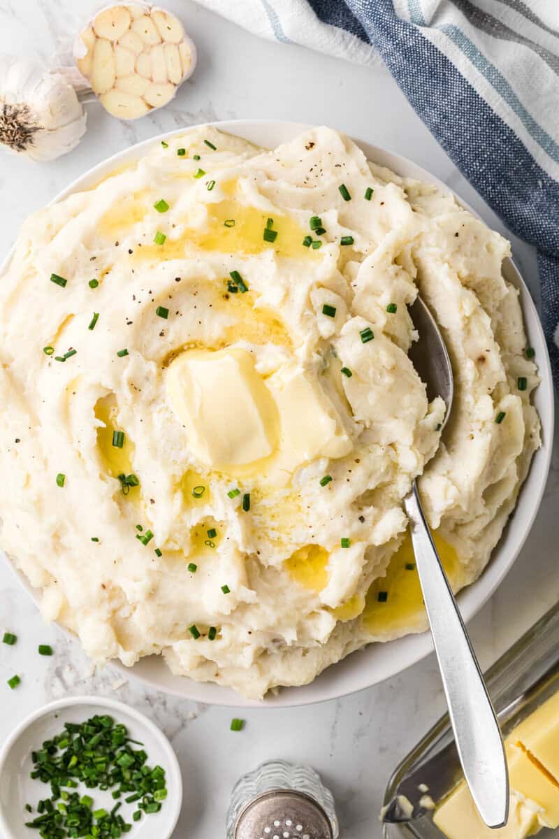 Garlic Mashed Potatoes served in large white bowl topped with butter.