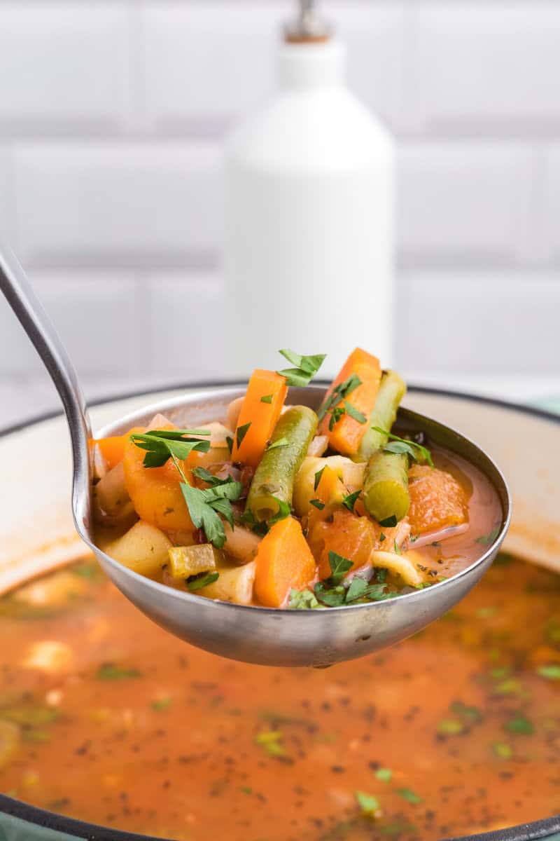 serving the minestrone with a metal ladle.