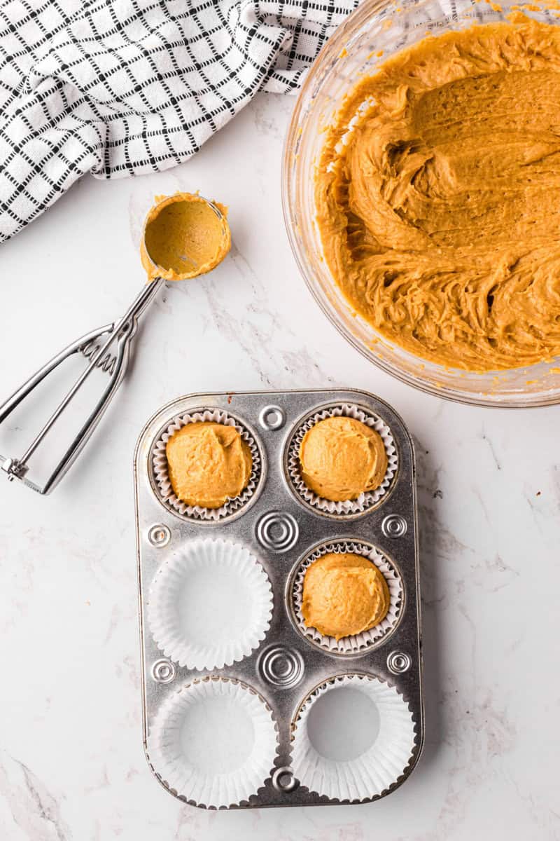 filling the cupcake liners with the batter in the cupcake pan.