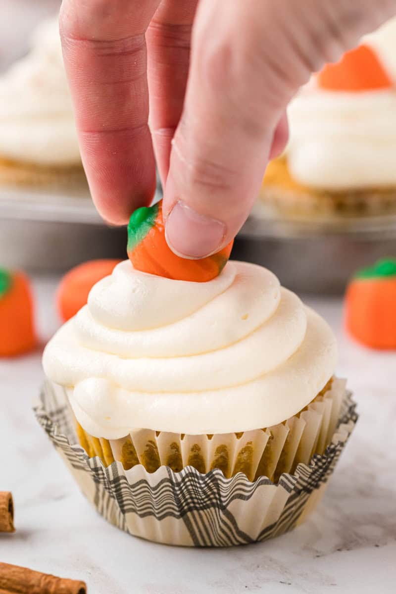 topping the cupcake with a candy pumpkin.