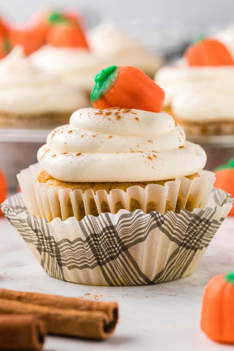 closeup of a pumpkin cupcake decorated with frosting and a pumpkin candy.