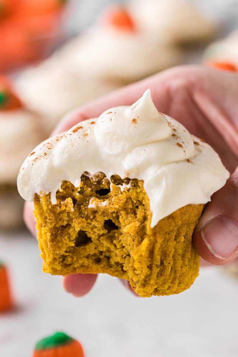 closeup of a pumpkin cupcake with a bite taken out of it.