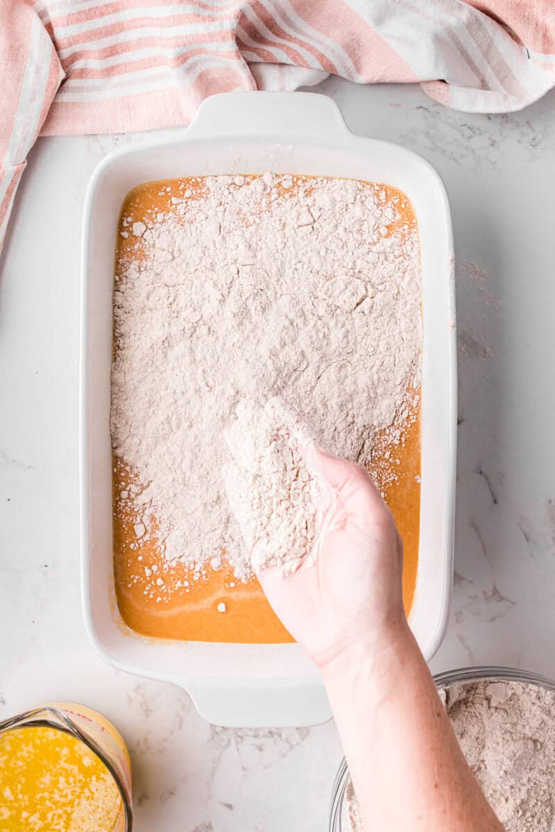 sprinkling the cake batter on top of the pumpkin mix.