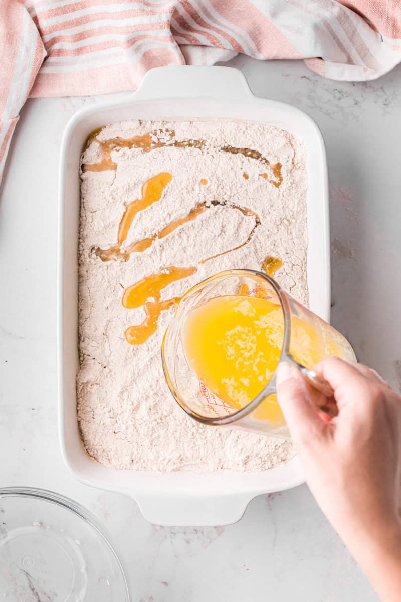 pouring the melted butter on top of the cake mix.