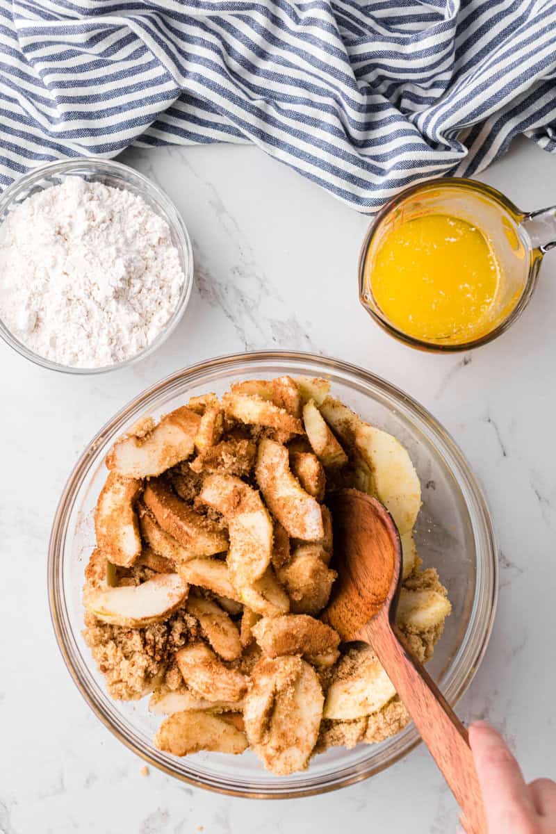 mixing the apples in with the spices and sugars.
