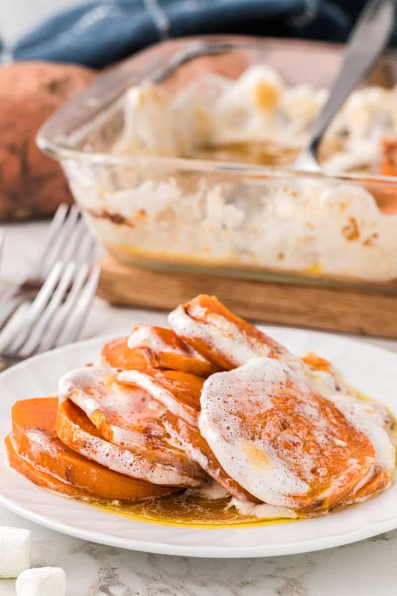 serving the candied yams on a white plate.