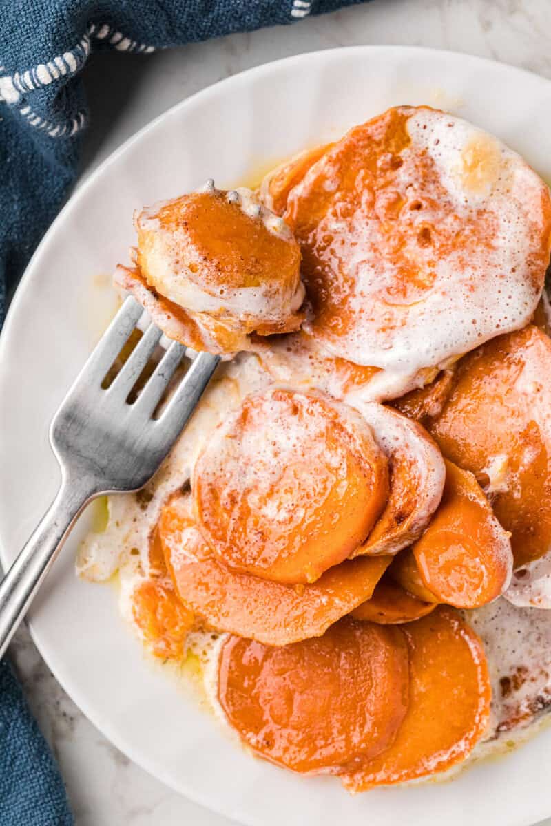 candied yams on white plate being eaten with a fork.