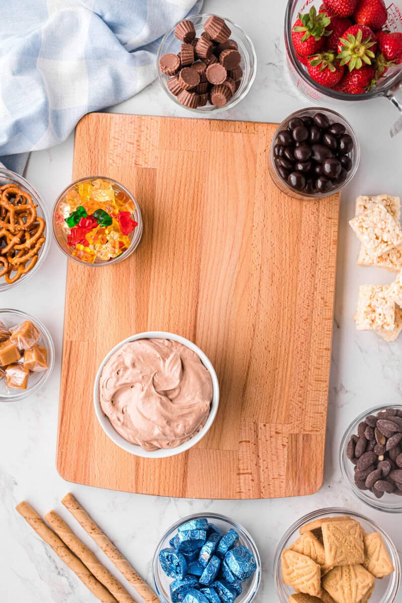 placing the bowls of ingredients and dip on the charcuterie board.