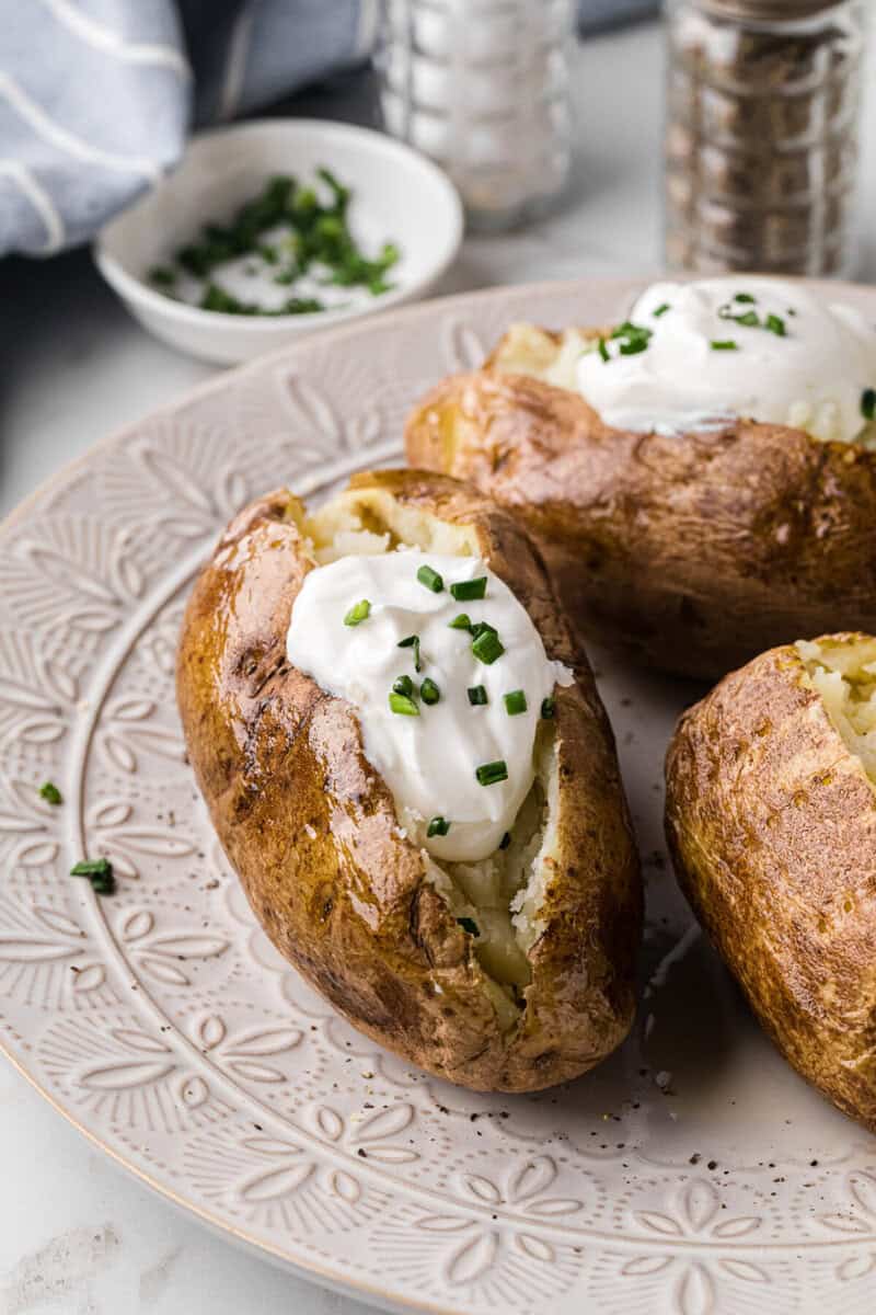 closeup of a baked potatoes topped with sour cream.