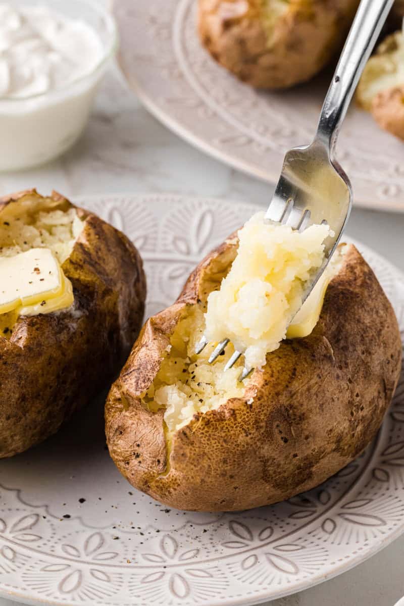 using a fork to fluff the baked potatoes.