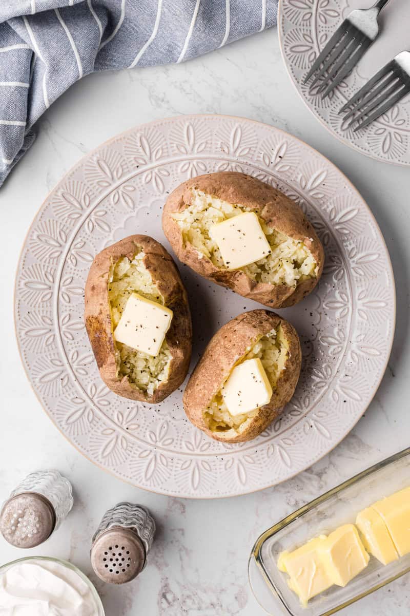 preparing baked potatoes with butter and salt and pepper.