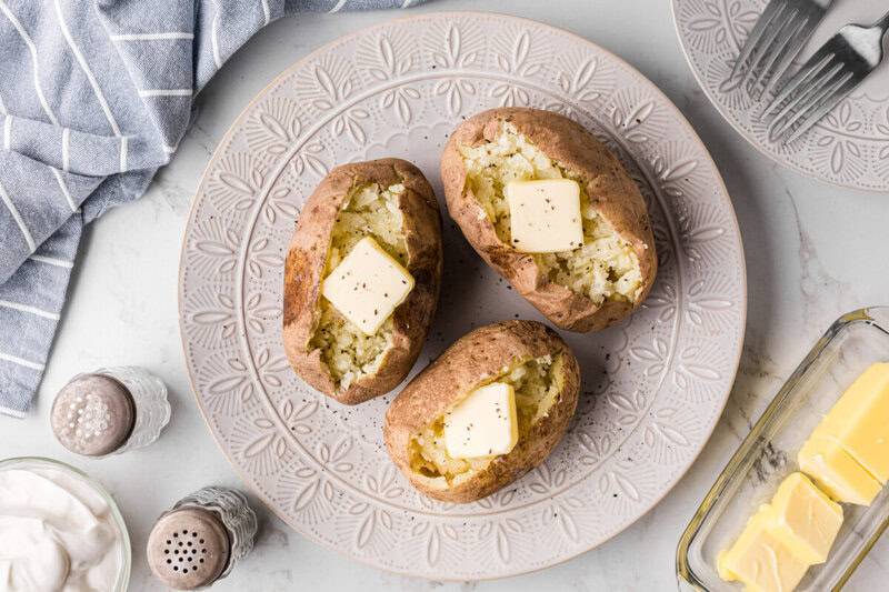 top-down view of 3 baked potatoes on white plate.