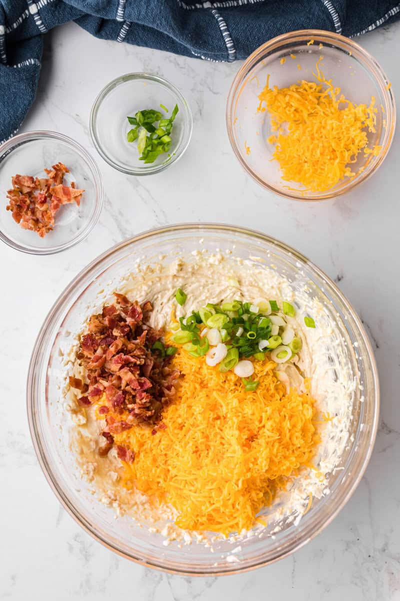 adding the cheese, bacon, and green onions to the dip.