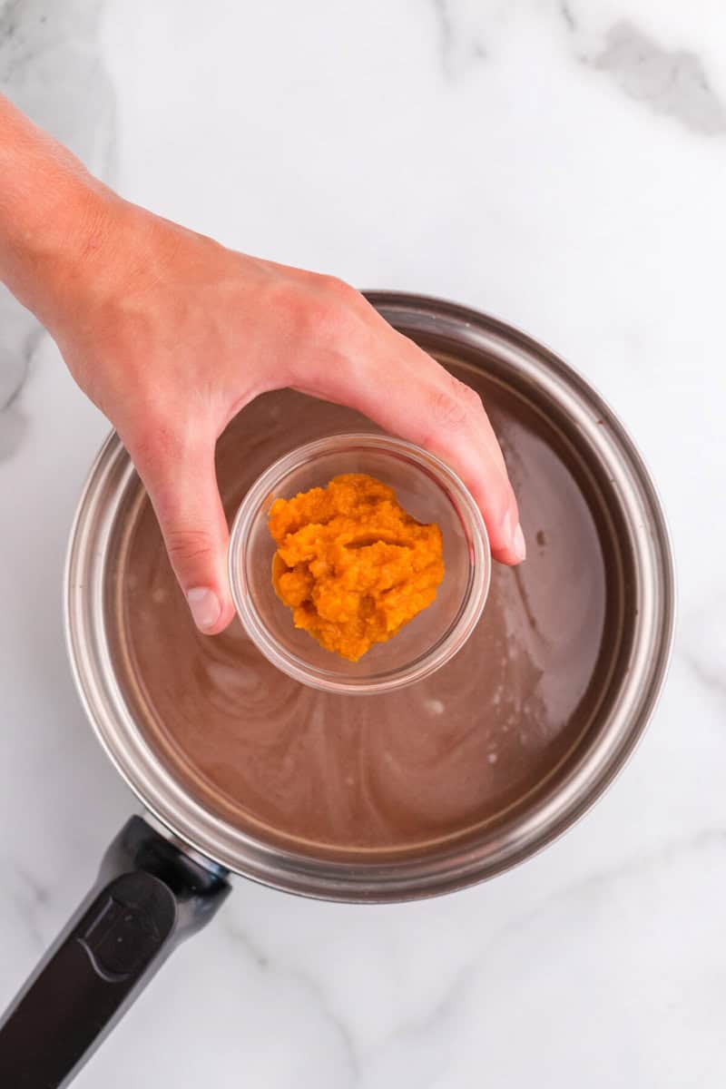 adding the pumpkin puree to the hot chocolate.