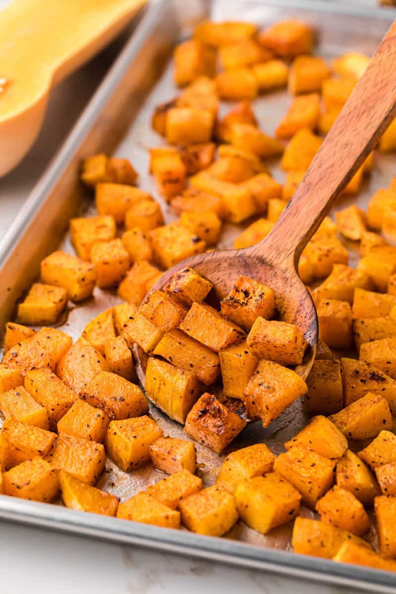 closeup of the roasted butternut squash being served with a wooden spoon