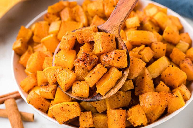 serving the roasted butternut squash with a wooden spoon.