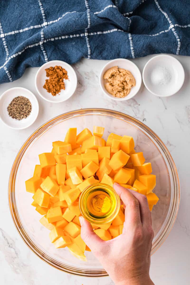 adding the oil to the butternut squash.