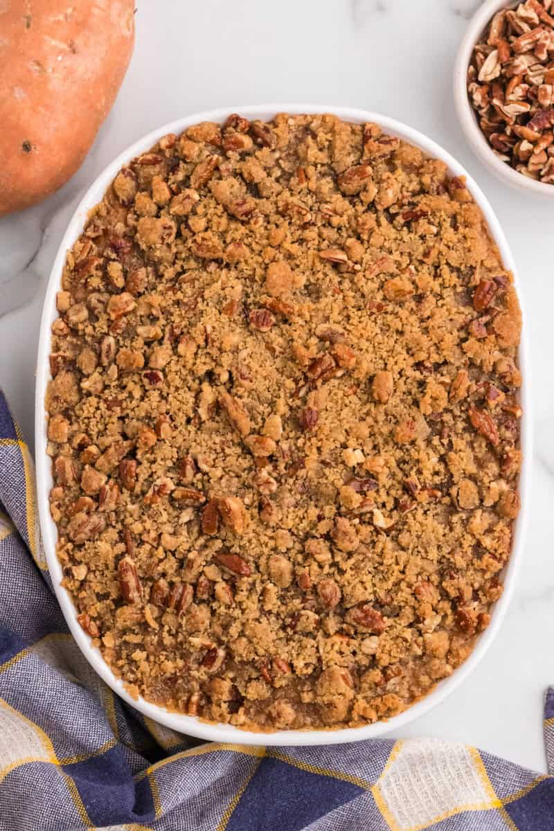 adding the pecan topping to the sweet potato casserole before baking.