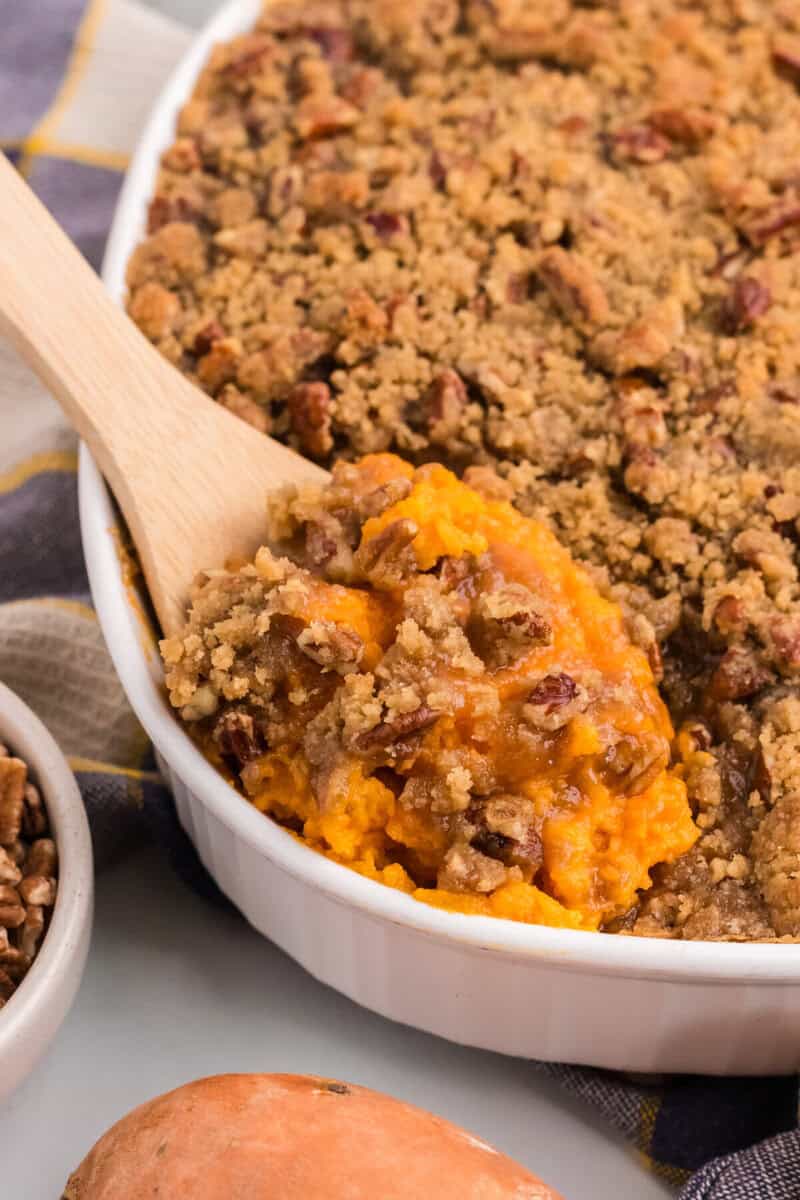 closeup of the sweet potato casserole being served with a wooden spoon.