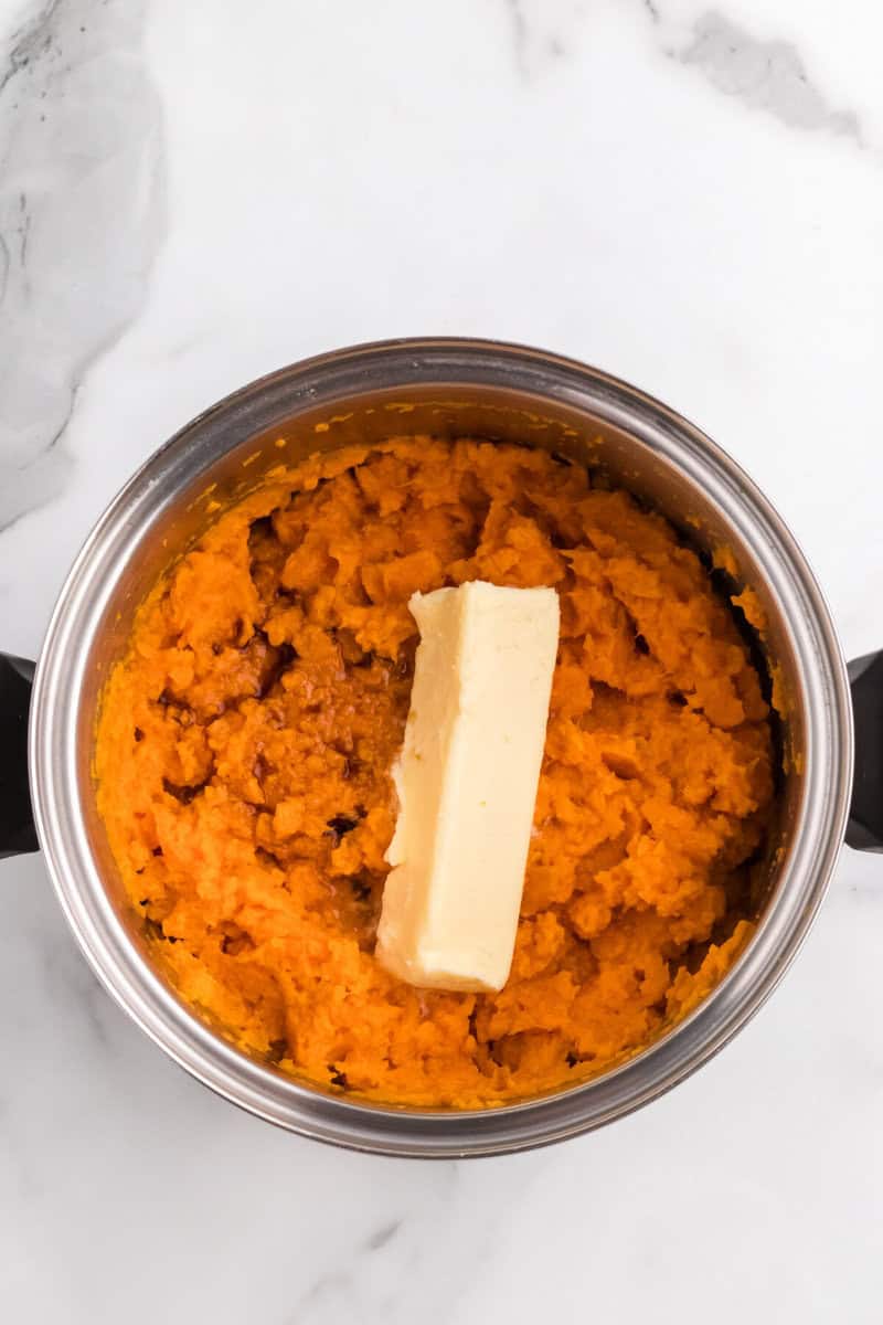 adding butter to the mashed sweet potatoes.