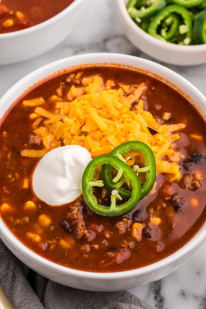 closeup of the taco soup topped with sour cream, cheese and two slices of fresh jalapeno.