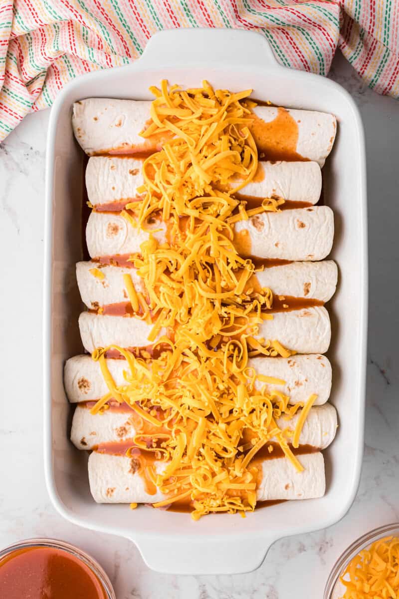 the beef enchiladas in the bottom of the baking dish topped with sauce and cheese.