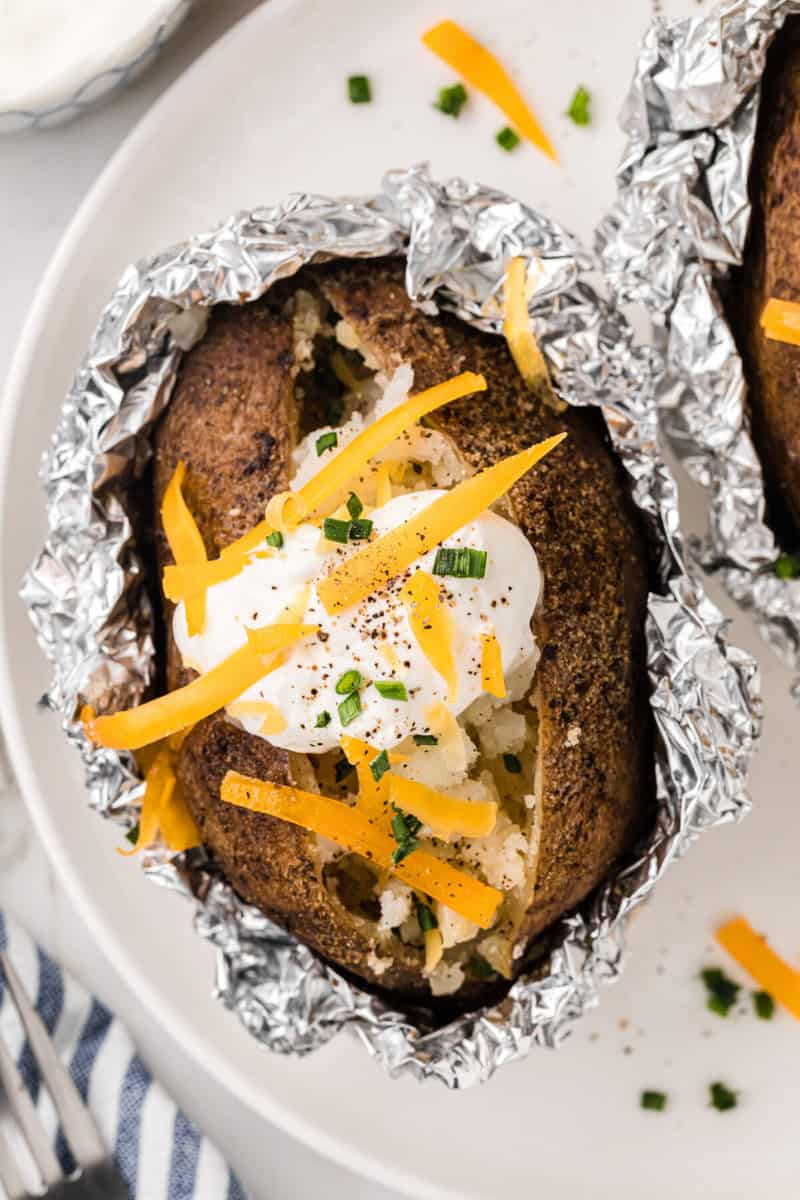 closeup of a baked potato on a white plate.