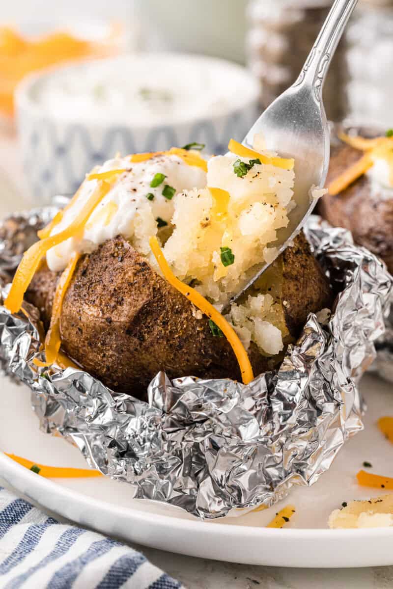 using a fork to eat the baked potato.