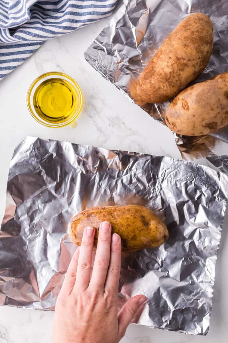 rubbing the olive oil on top of the potatoes.