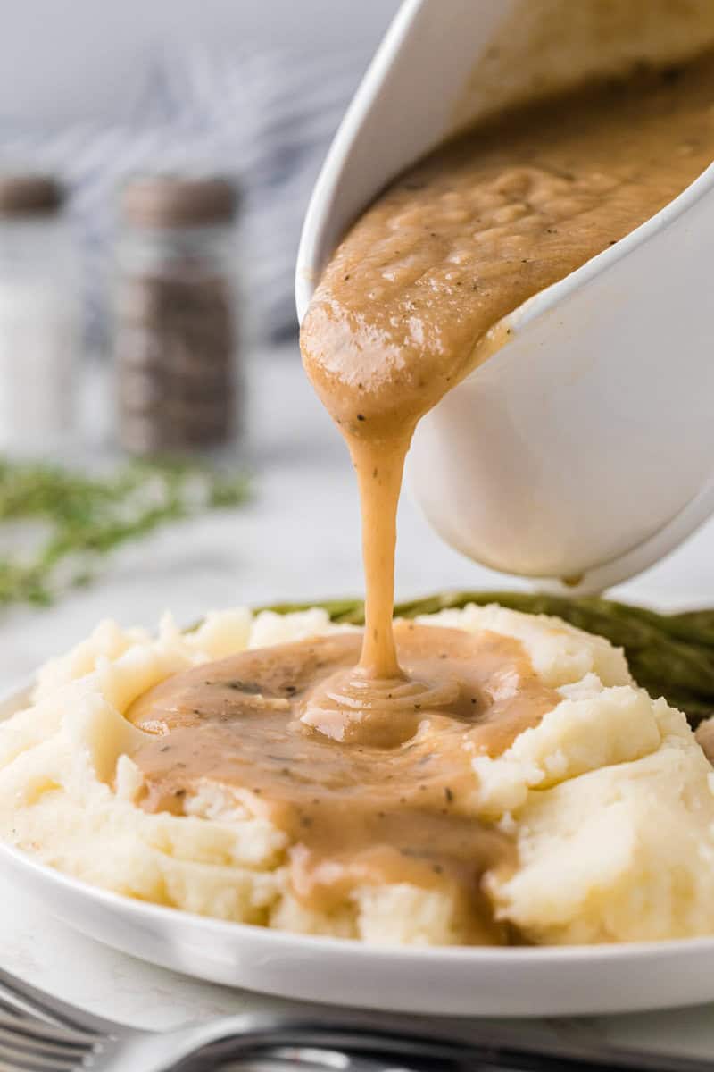 pouring the gravy on to mashed potatoes.