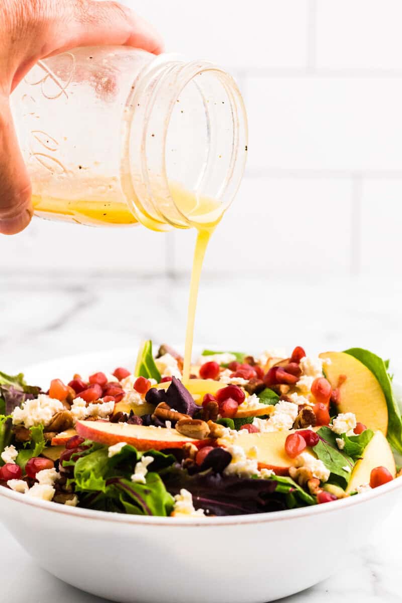 pouring the dressing on top of the salad.