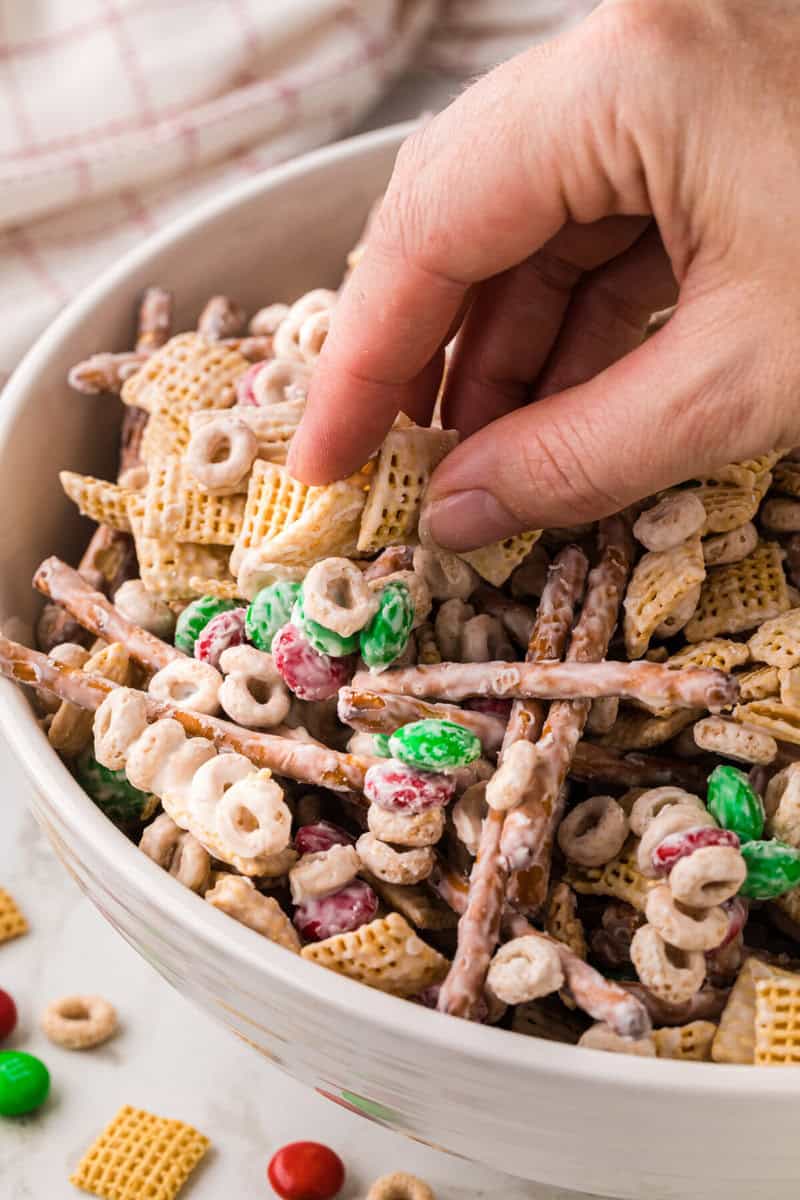 grabbing a handful of the Chex Mix from the bowl.