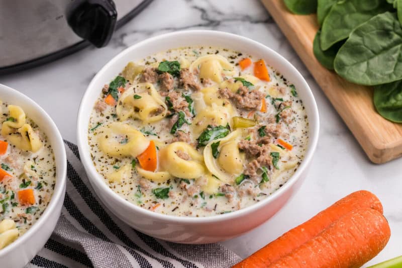 creamy sausage tortellini soup served in a white bowl.