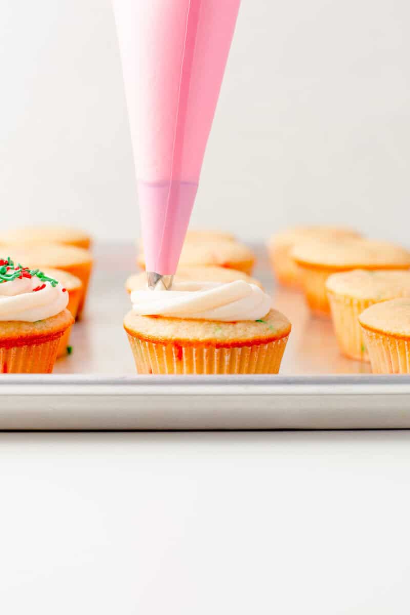 icing the cupcakes with a piping bag.