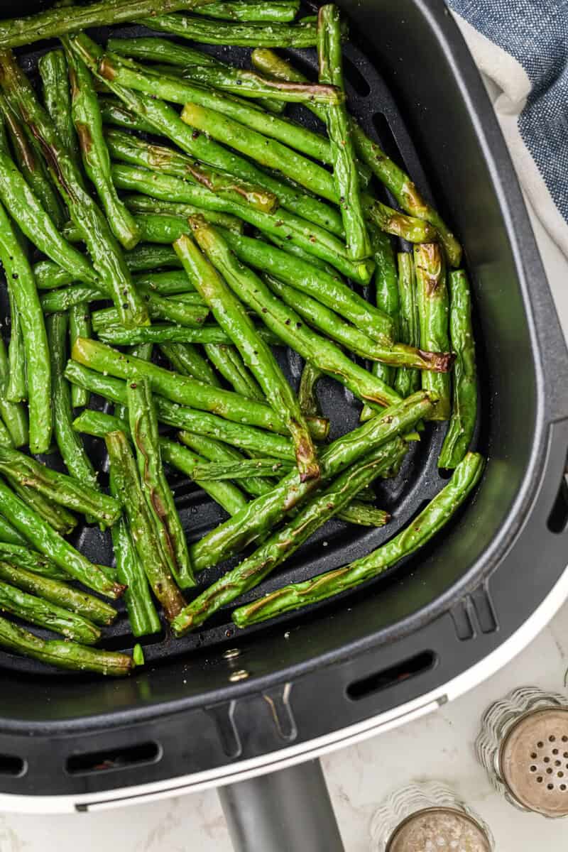 closeup; of the air fryer green beans cooked in the air fryer.