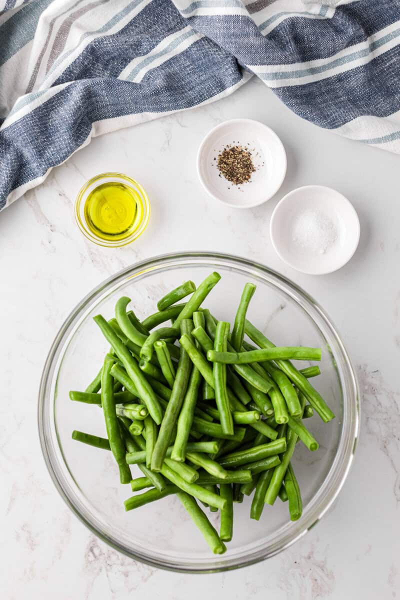 green beans in a glass bowl to be mixed with the oil, salt and pepper.