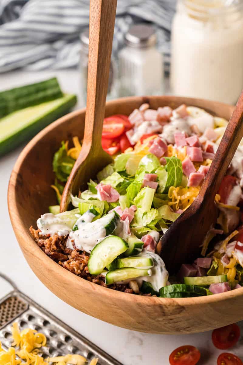 tossing the Chef salad with wooden salad tongs.