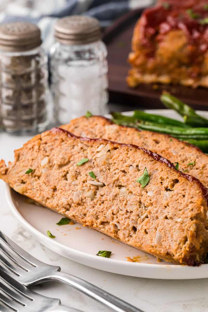 closeup of a slice of turkey meatloaf on a white plate.