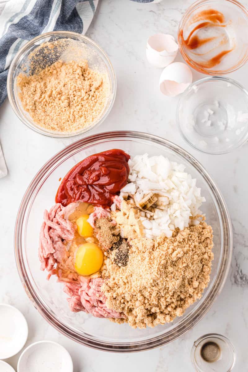 ingredients for the meatloaf in a large glass bowl for mixing together.