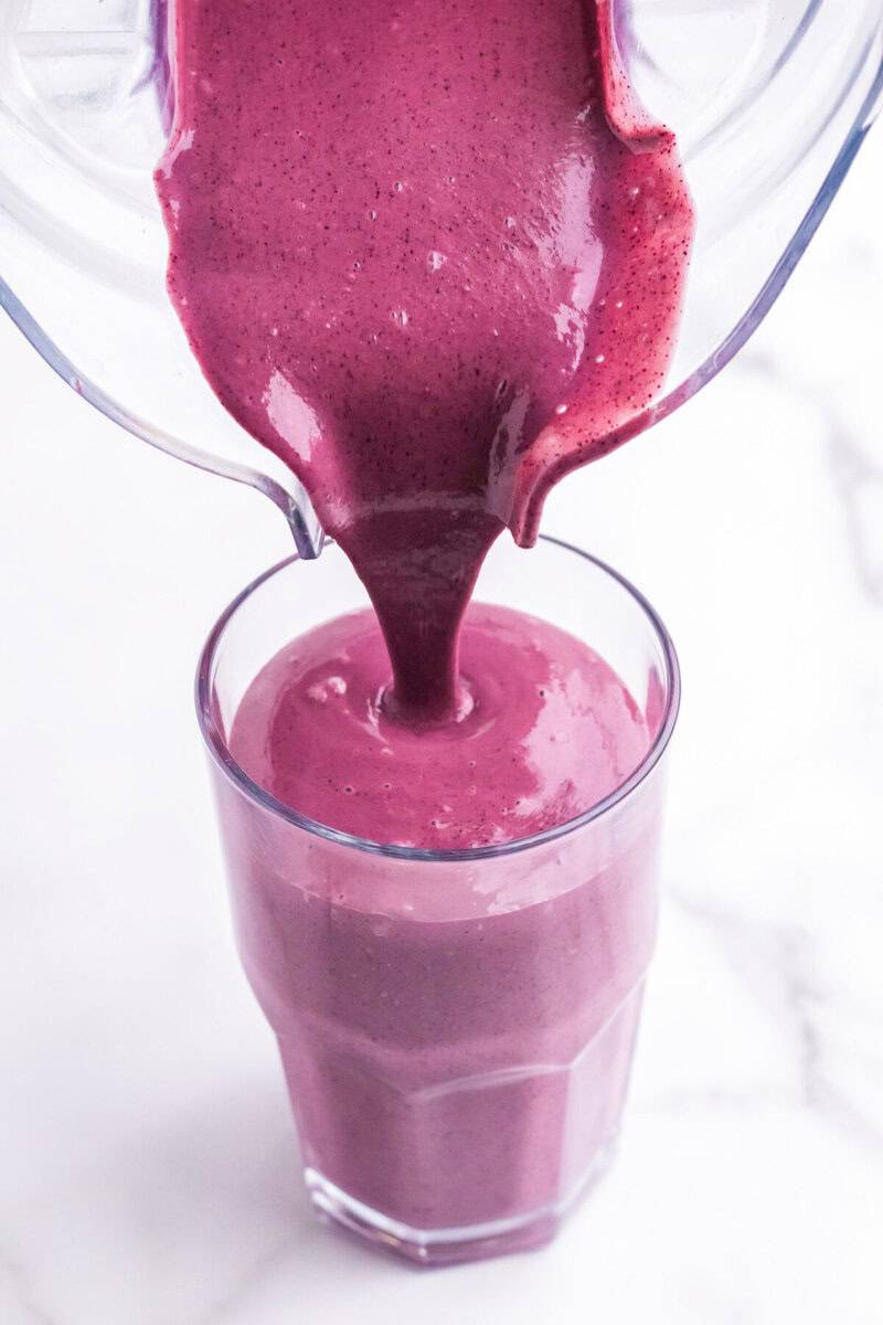 pouring the Blueberry Spinach Smoothie into the glass.