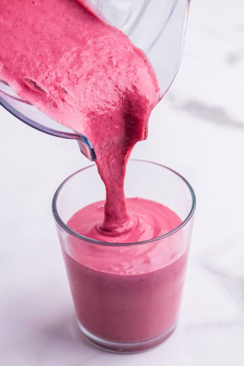 pouring the smoothie from the blender into a glass.