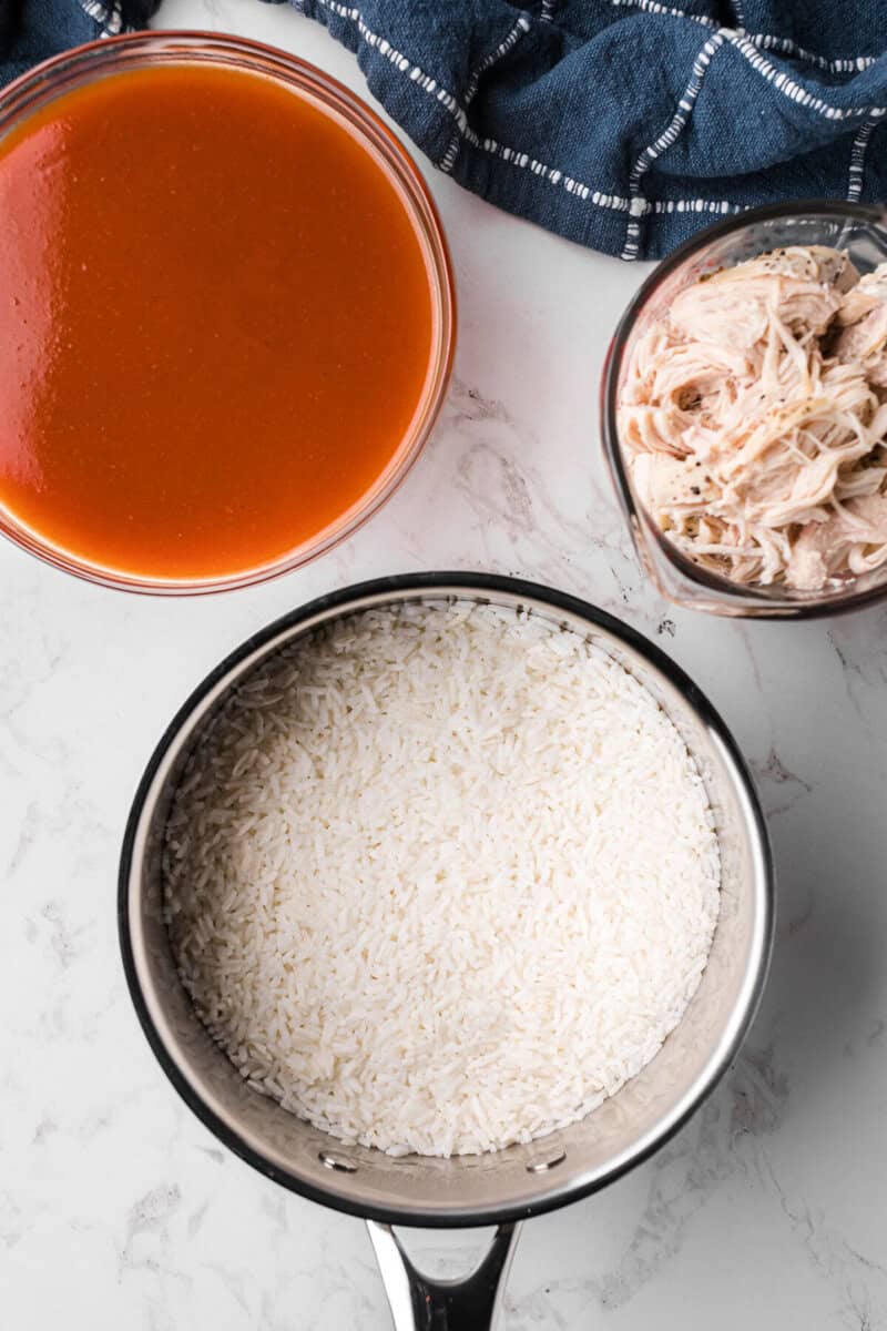 rice cooked in a pot with sauce and chicken on the side.