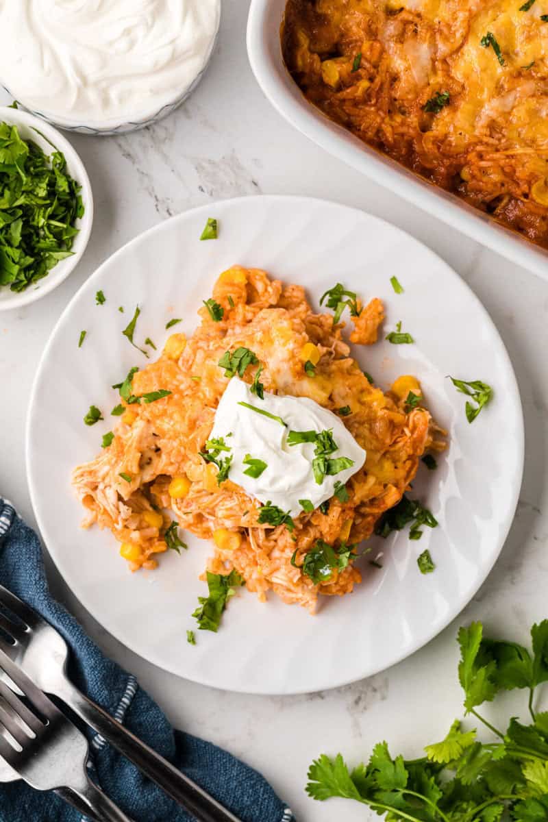 top-down view of the chicken enchilada casserole served on a white plate with sour cream.