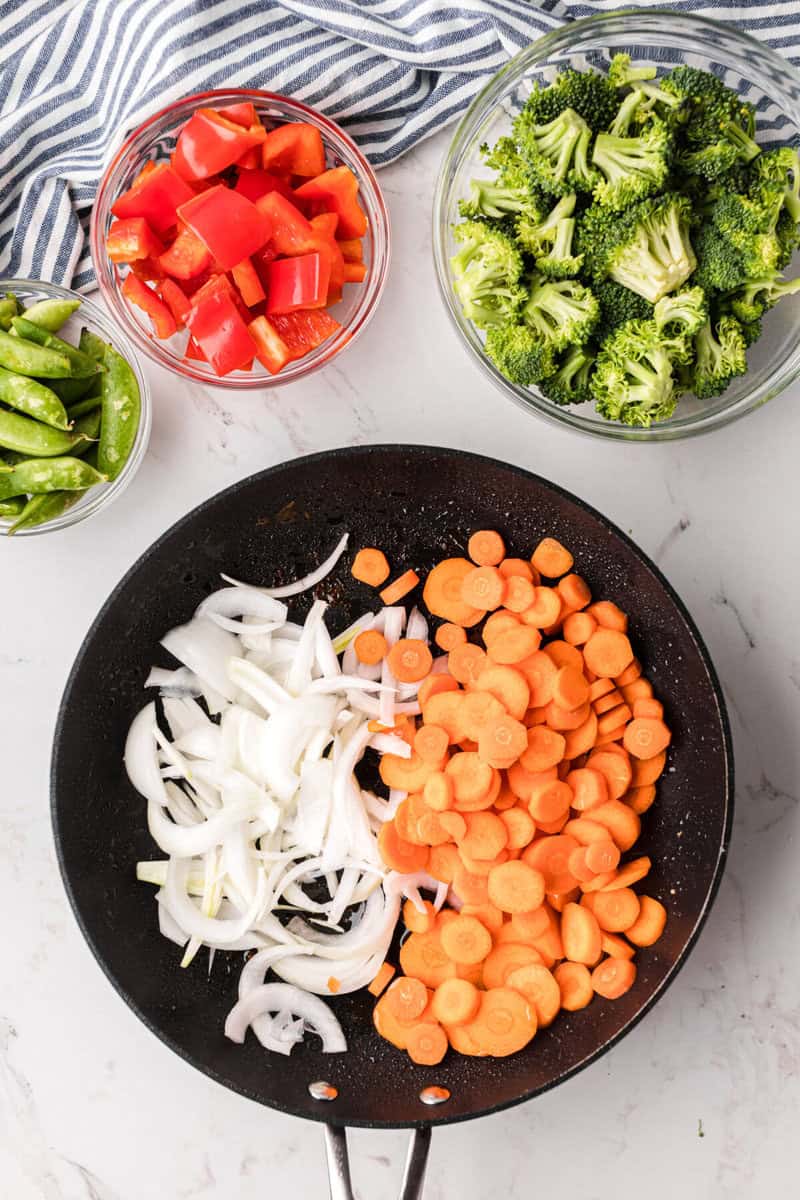 cooking the onions and carrots in the skillet.