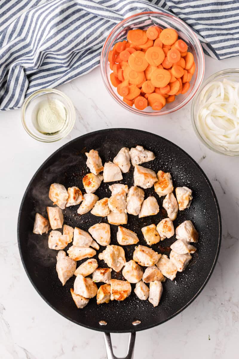 cooking the chicken in the skillet.