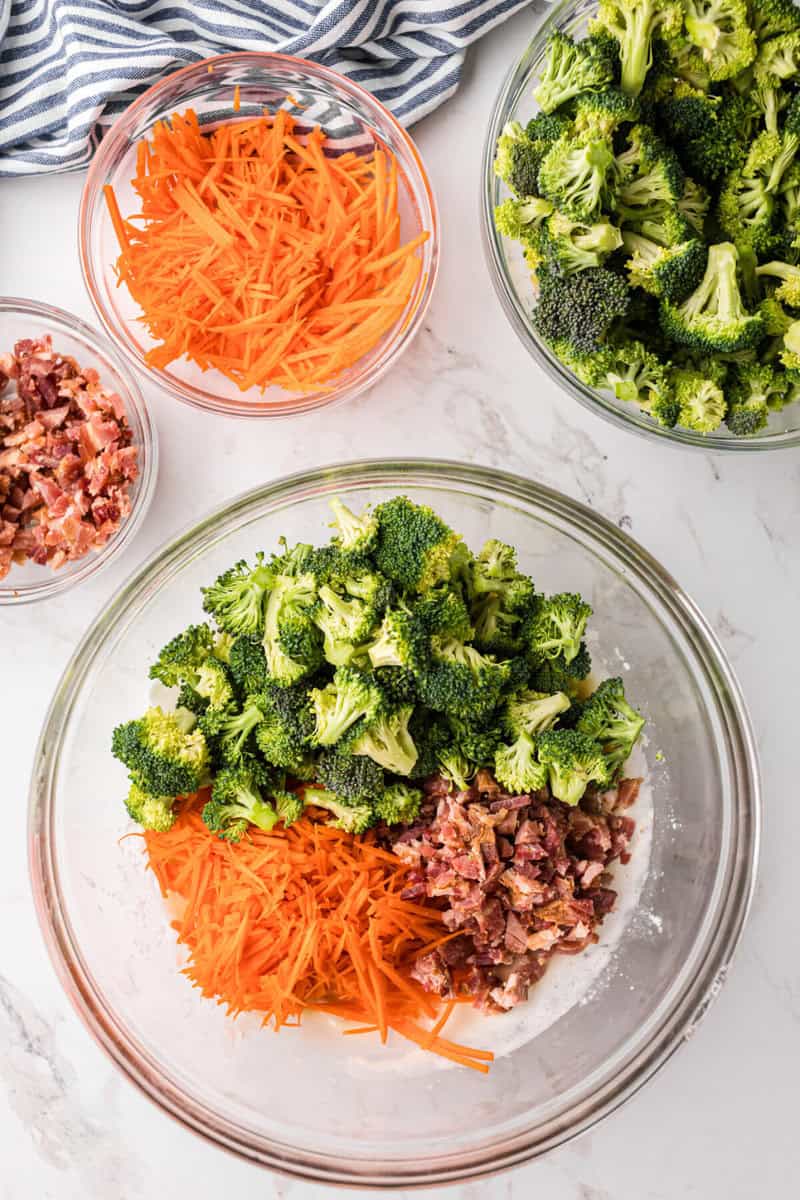 adding the broccoli, bacon, and carrots to the bowl with the dressing.